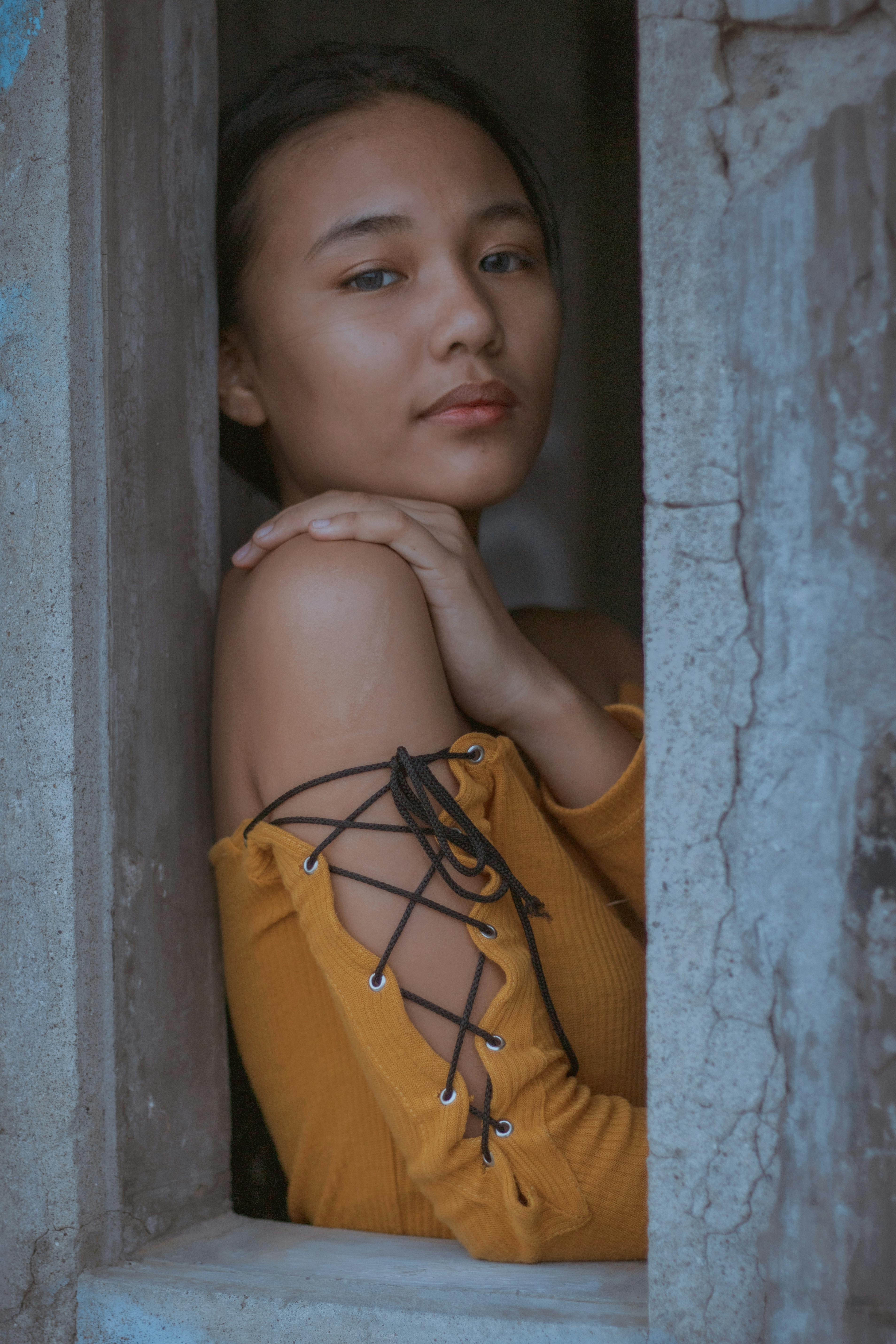 ethnic teen girl touching shoulder in shabby concrete building