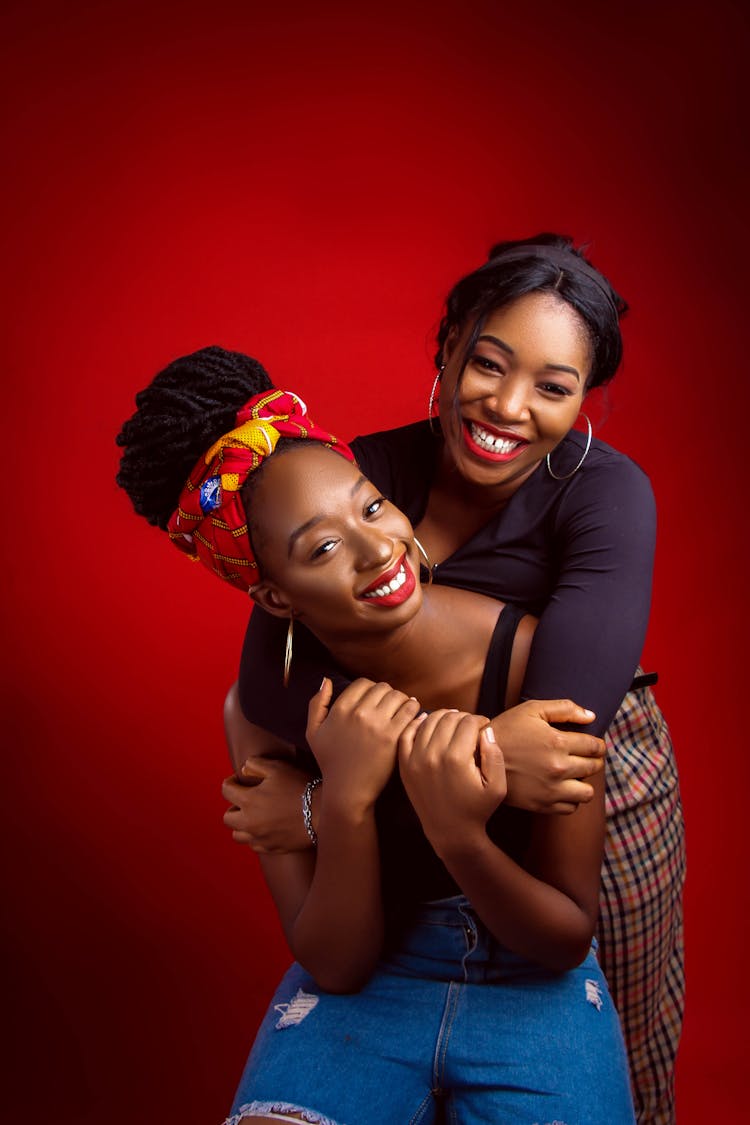 Smiling Black Women Embracing In Studio