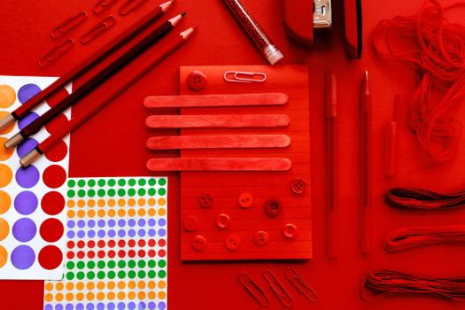 A creative flat lay of red stationery items including pencils, paper clips, and more.