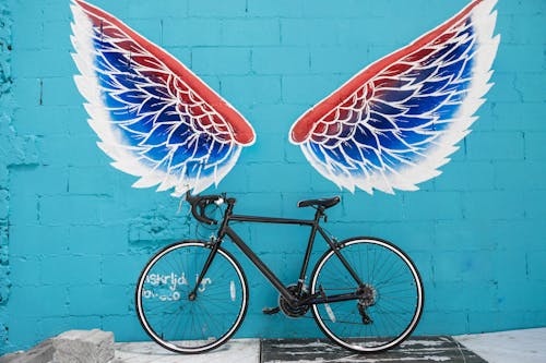 Black Road Bike Leaning on Red-blue-and-white Wing Graffiti Wall