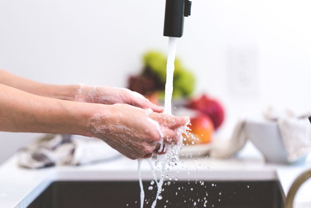 Persona lavándose las manos con agua y jabón
