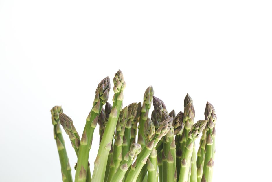 Roasted asparagus spears with lightly charred tips arranged on a parchment-lined baking sheet, drizzled with olive oil and flaked salt.