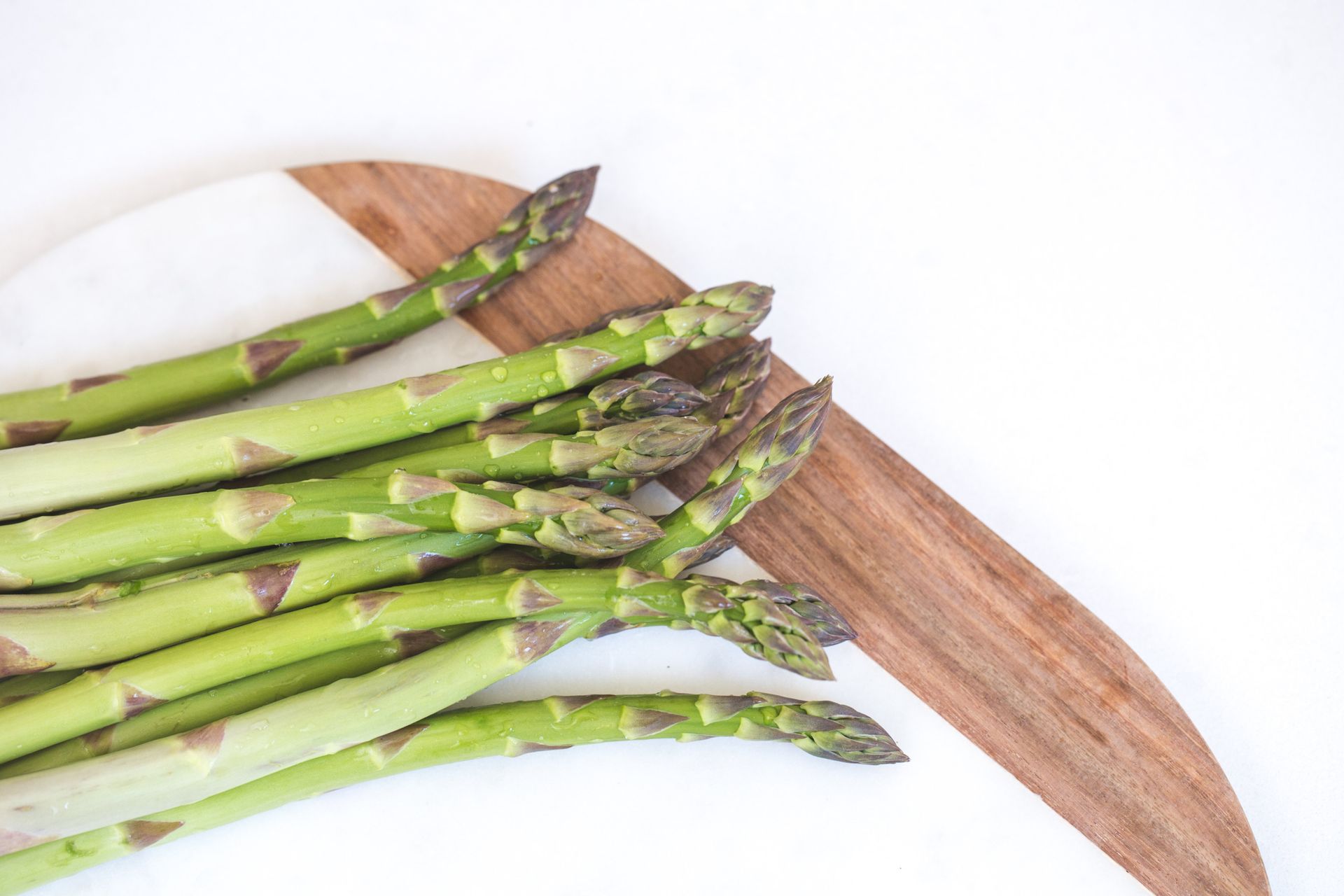 Fresh asparagus spears on a wooden cutting board, perfect for healthy recipes and meal prep.