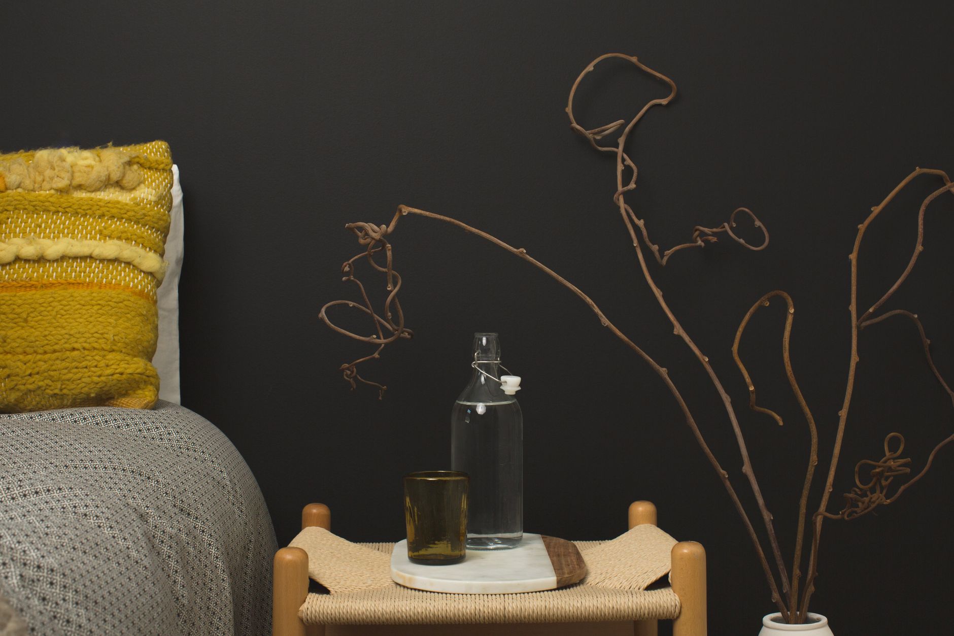 A cozy modern bedroom with minimalist decor, showcasing a knitted pillow and rustic furniture.