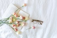 白色背景的公寓里，摆放着精致的鲜花、打开的书和眼镜，显得十分美观