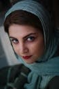 一位黑发蓝眼、戴着头巾的年轻女性，正沉思着望向镜头