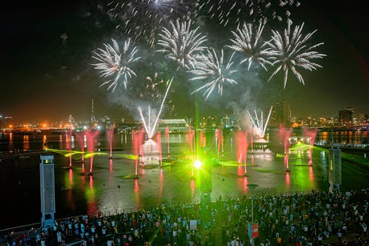 A breathtaking fireworks show lights up the night sky over a bustling city and vibrant crowd.