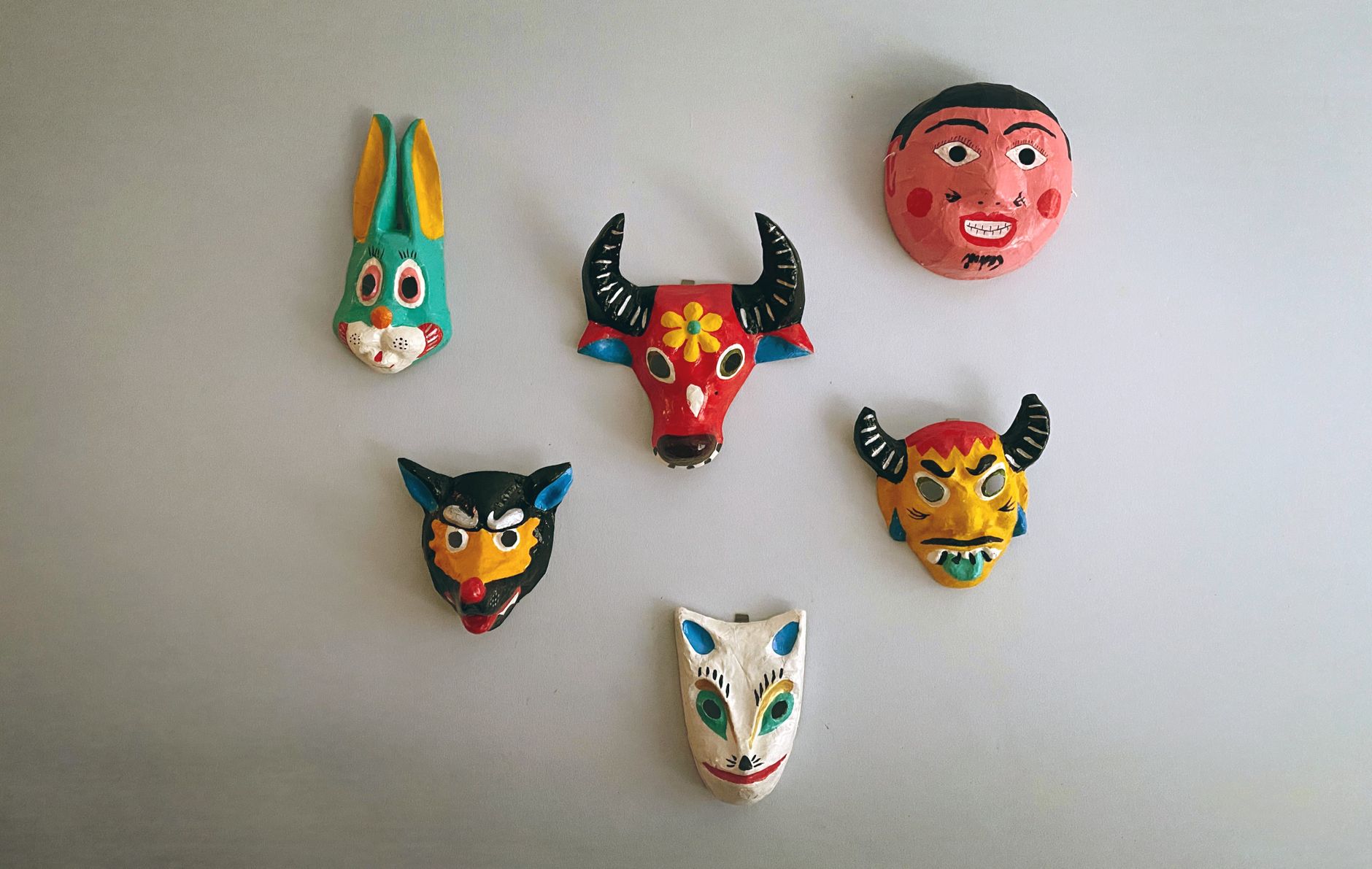Vibrant collection of artistic papier-mâché masks on a white background.