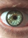 Closeup shot of crop faceless male gazing attentively at camera with widely opened green eye
