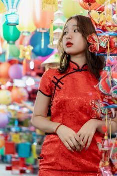 一位身着优雅红色连衣裙的沉思少女，正站在各式明亮的灯笼间眺望远方
