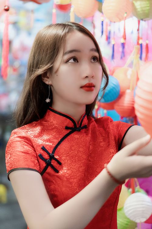 Free Dreamy Asian female teen with makeup in trendy wear touching colorful lantern while looking up Stock Photo