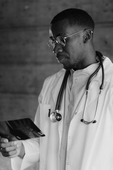 Monochrome image of a doctor examining an X-ray, wearing a stethoscope and lab coat.