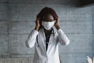 女医护人员在室内调整口罩，展现了医疗专业精神
