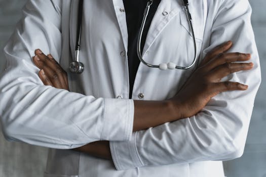 Close-up of a confident doctor in a lab coat standing with crossed arms and stethoscope.