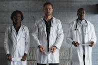 Man in White Coat Standing Beside Gray Wall