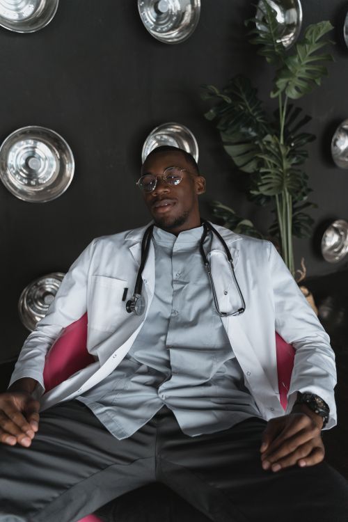 Free African American male doctor in a modern setting, looking relaxed in a lab coat with stethoscope. Stock Photo