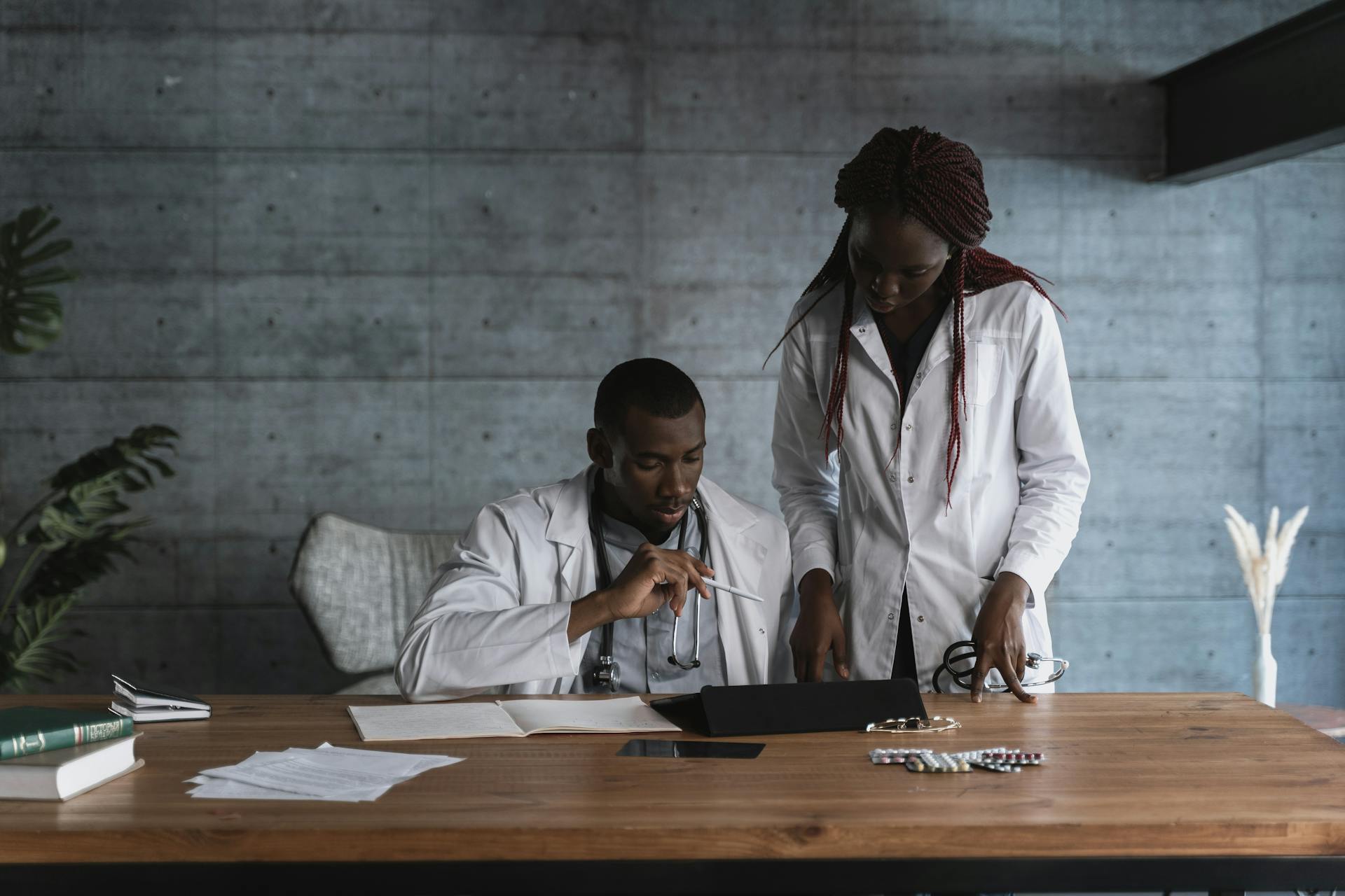 Two doctors reviewing patient information on a tablet in a modern office setting.