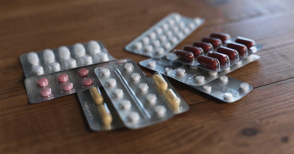 Several blister packs of pills and capsules arranged on a wooden table