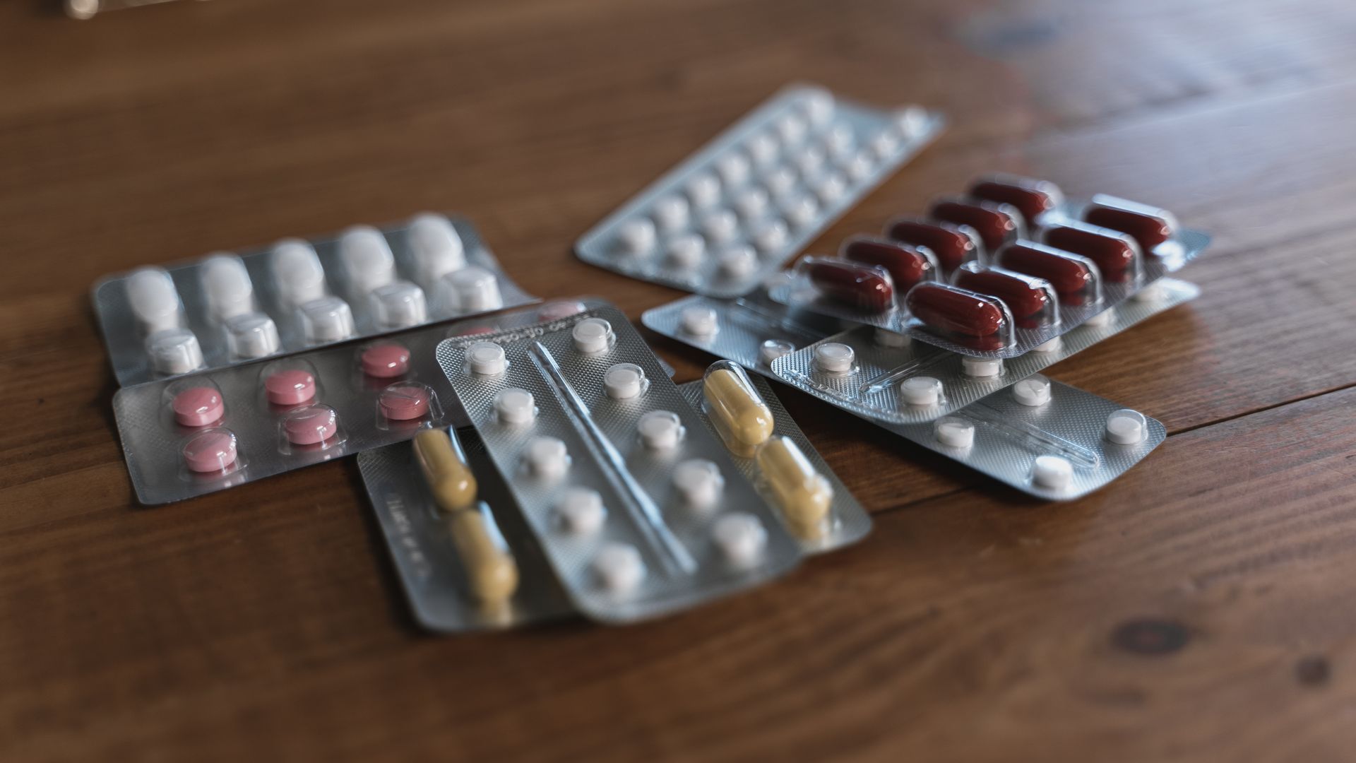 A variety of pills in blister packs displayed on a wooden surface. Ideal for health-related content — modvigil 200mg review