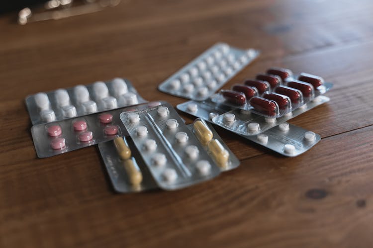 Assorted Packs Of Pills On A Wooden Table