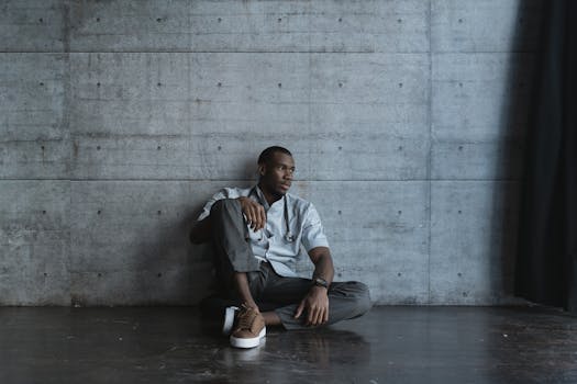 一位疲惫不堪的医生穿着医用制服，焦虑地坐在混凝土墙上