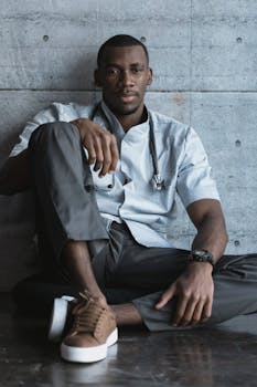 一位年轻医生随意地坐在纹理墙壁上，传递出专业又放松的感觉