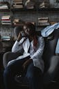 Woman in White Button Up Long Sleeve Shirt Sitting on Black Leather Armchair