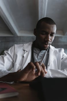 Focused black male doctor using a tablet in a modern office setting.