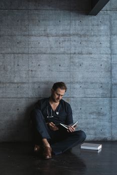 一位成年男医生在现代化、极简主义的房间里专注地看书，显得十分专业