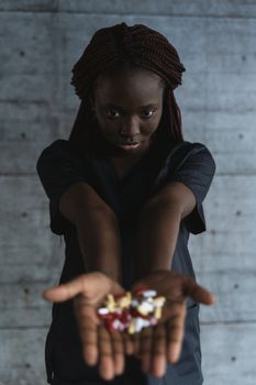 一位穿着手术服的非裔美国女医生站在室内，递上药丸
