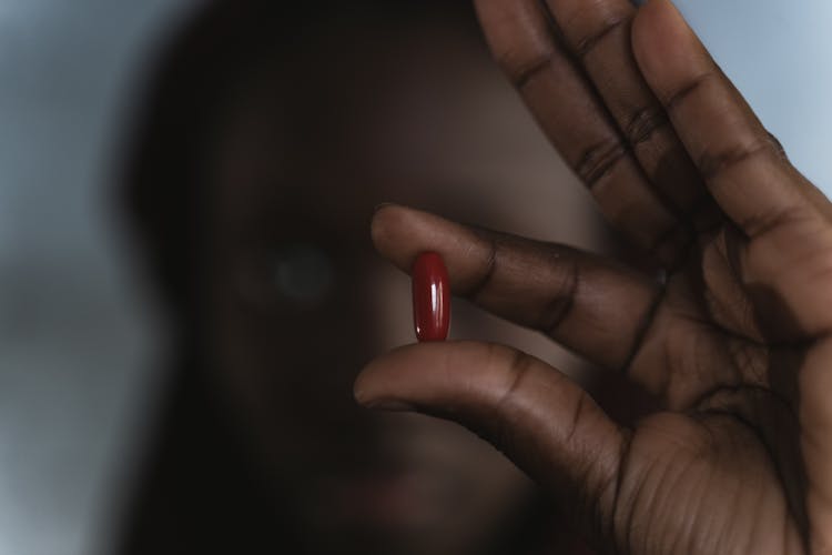 Close-Up Photo Of Person Holding A Red Pill