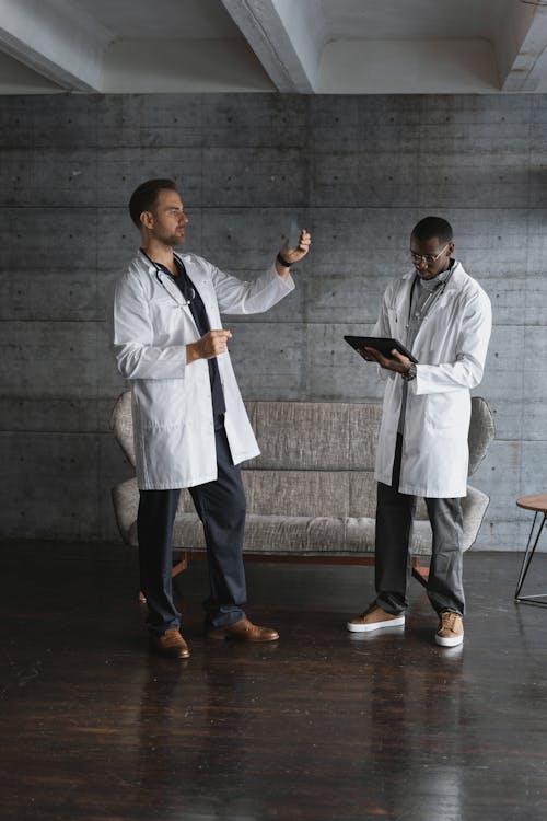 Free Men in White Robe with Stethoscopes Standing Near a Sofa Stock Photo