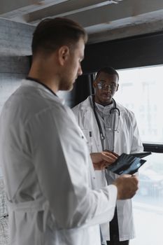 Two doctors in medical coats discussing x-ray results in a hospital setting.