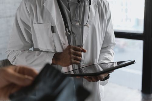 Free A professional medical practitioner holding a tablet, focused on work in a clinical setting. Stock Photo