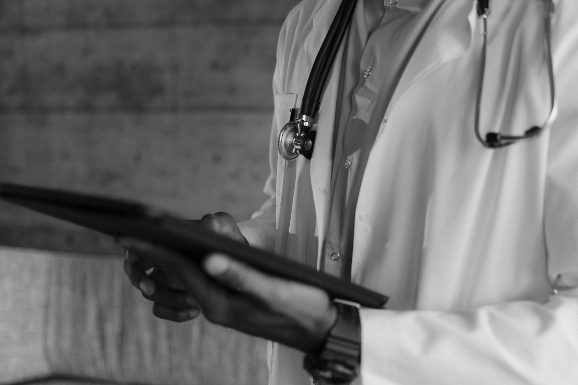 Black-and-white photo of a medical professional holding a tablet, focusing on digital health technology.