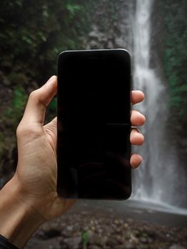 Crop faceless tourist taking photo of river flowing in tropical rainforest during vacation in  tropics