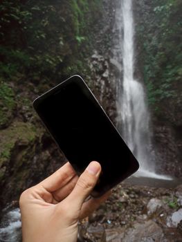 一名匿名旅行者站在森林峡谷的岩石旁，靠近从高处落下的河流