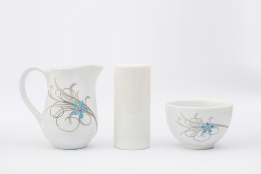 Minimalist ceramic tableware including a pitcher and bowl with delicate blue floral accents.
