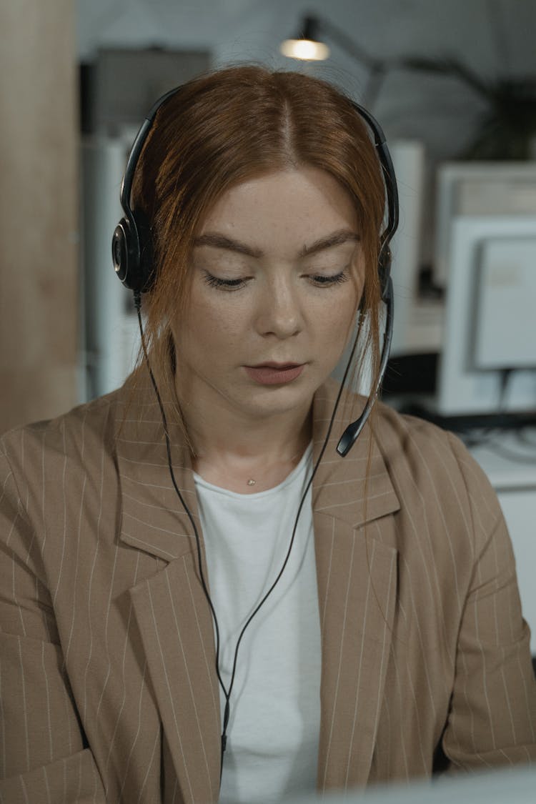 Close-Up Shot Of A Woman In Brown Plaid Blazer Wearing Black Headphones