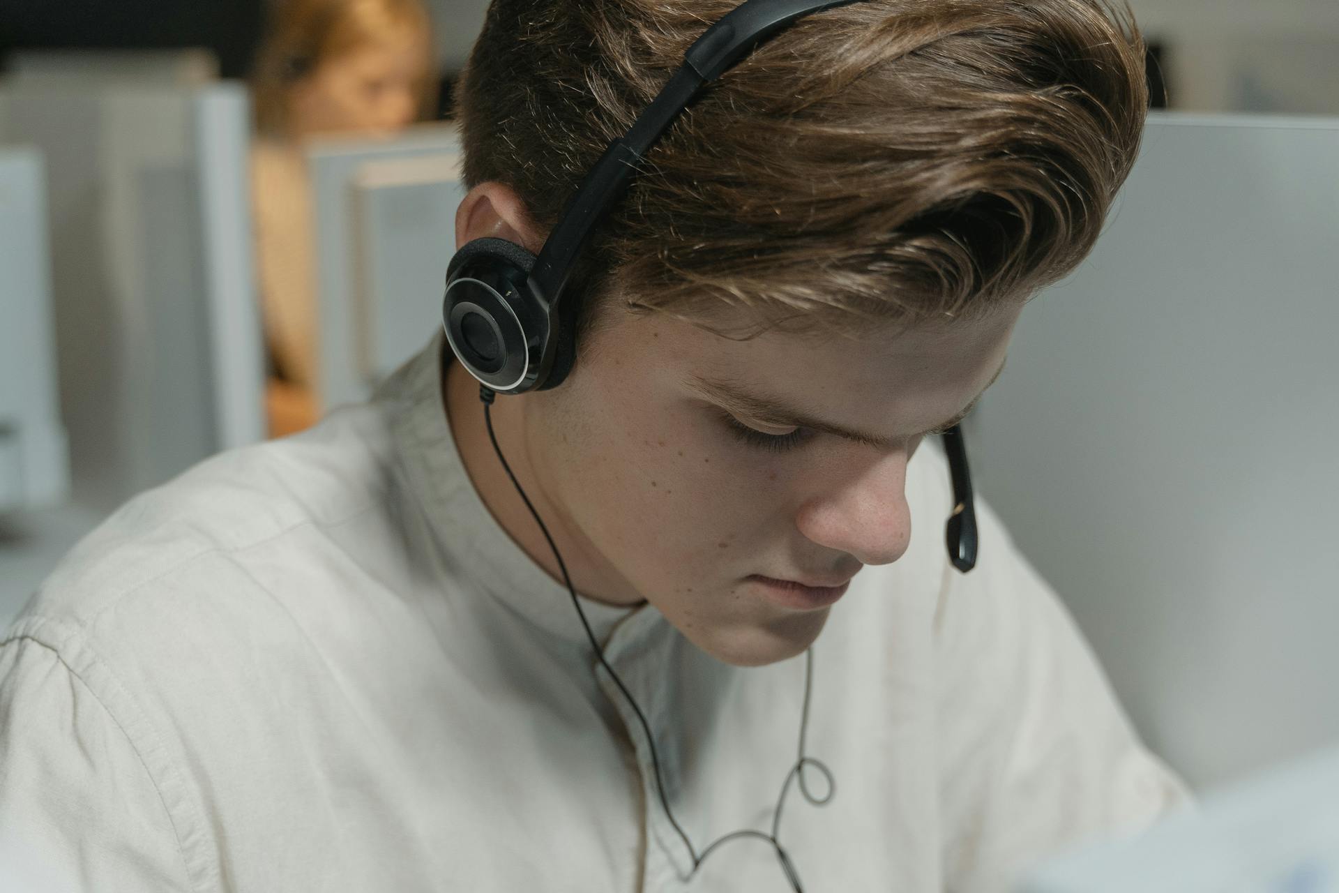 A call center agent wearing headphones focuses on providing customer support in an office setting.