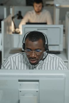 African American call center agent working intently with headset.