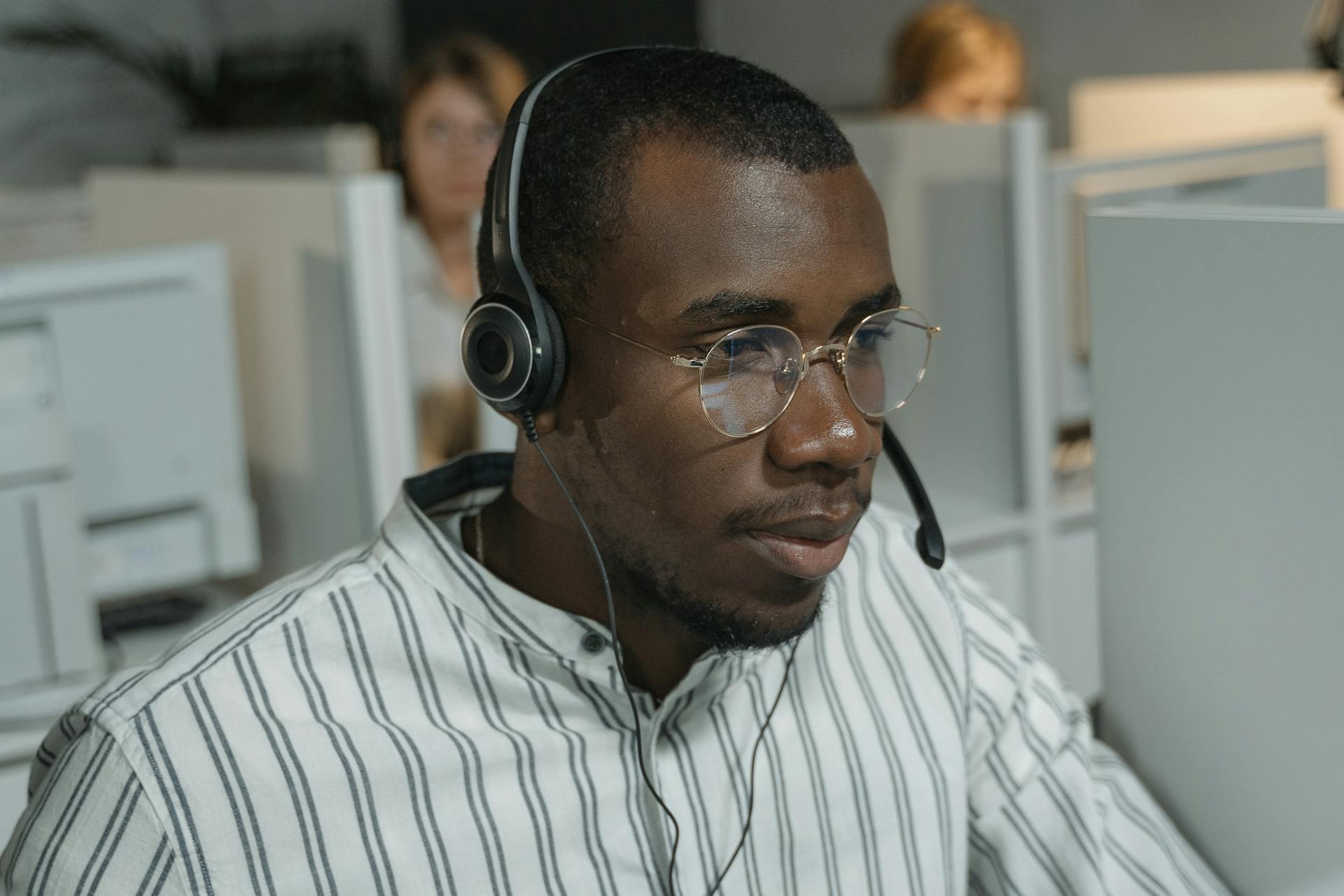 Professional call center agent with headset, focused on customer support tasks in a busy office.