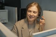 一位面带微笑的女呼叫中心工作人员戴着耳机，在办公室里协助客户