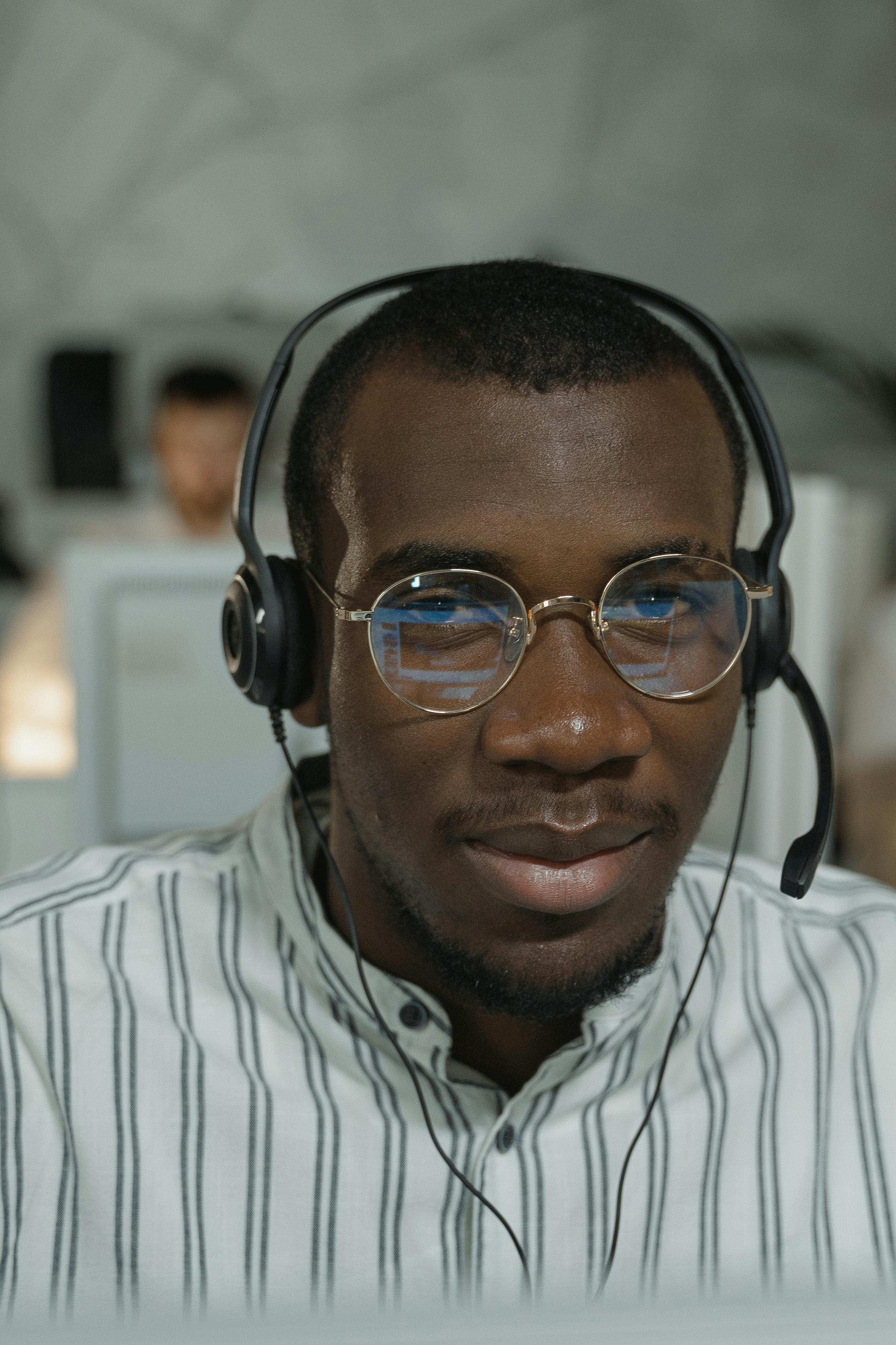 a man in white and black striped button up shirt wearing black framed eyeglasses