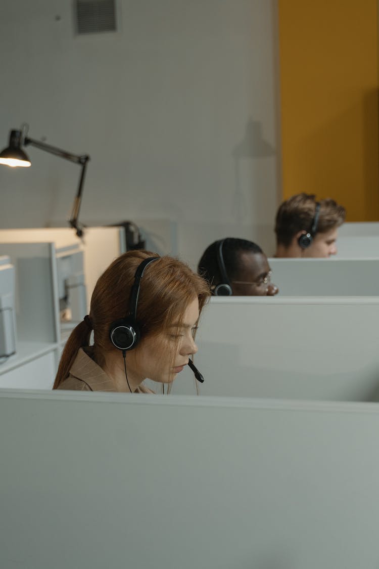 A Woman With Headset Inside A Gray Cubicle