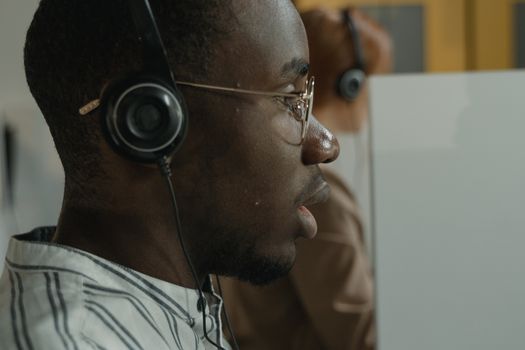 Side view of a focused customer service representative wearing a headset in a call center.