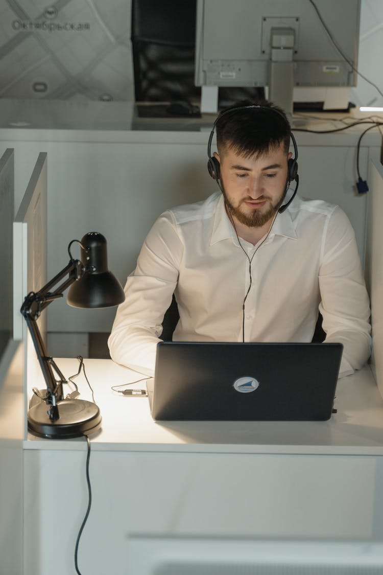 Man In White Long Sleeves Wearing Headphones While Working In The Office