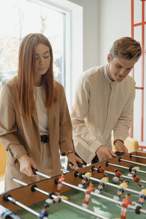 Free Two young adults enjoying a game of table football in a bright indoor setting. Stock Photo