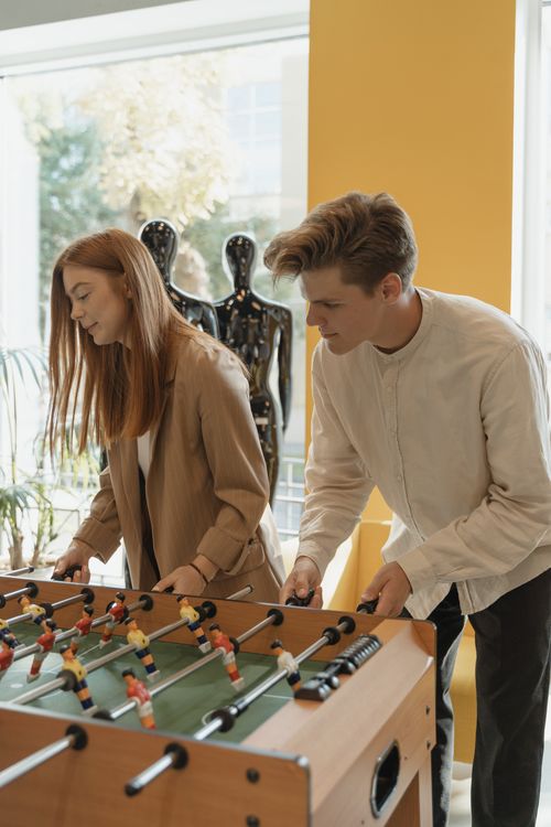 Free Young couple playing table football indoors, enjoying leisure time together. Stock Photo