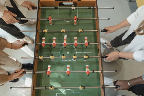 Free A group of adults playing table soccer indoors, showcasing friendship and fun. Stock Photo